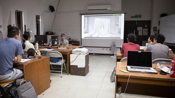 博鈞以他在南藝的創作及接案作品為例，分享他的心路歷程。投影幕上是他的獨立製作作品《電傳托邦》