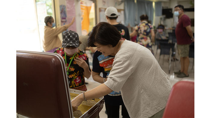 長榮社區發展協會的潘美純老師，和當年的眷村居民一起翻看老照片，回憶眷村生活點滴。